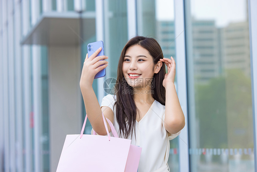 青年女性逛街拎购物袋手机自拍图片