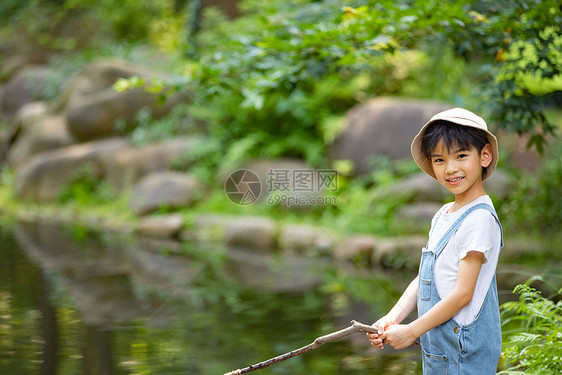 在户外小溪边钓鱼的小男孩图片