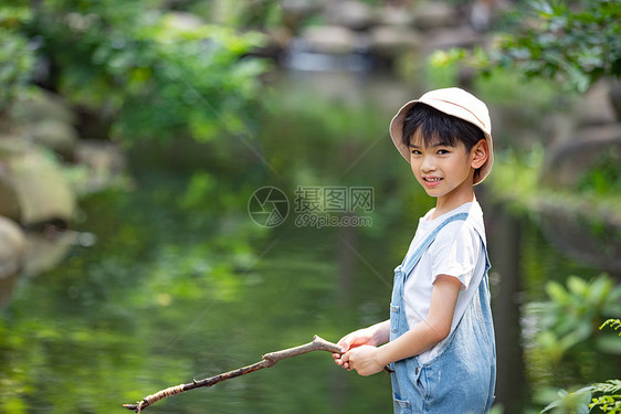 在户外小溪边钓鱼的小男孩图片