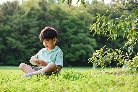 小男孩坐在草地上画面图片