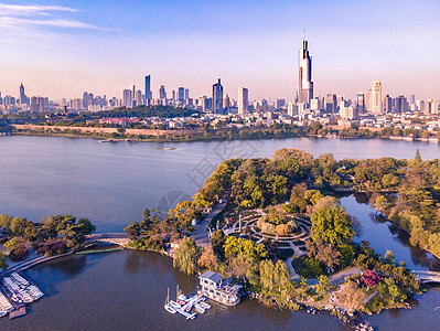 现代公园晨光里的南京玄武湖与地标建筑紫峰大厦背景