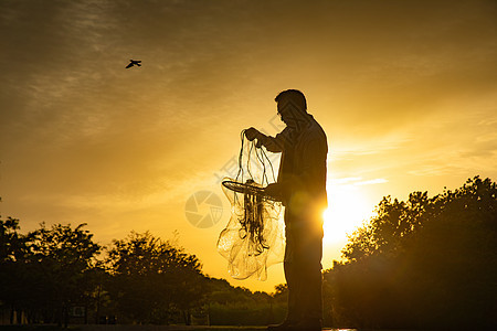 夕阳下整理渔具的中年人图片