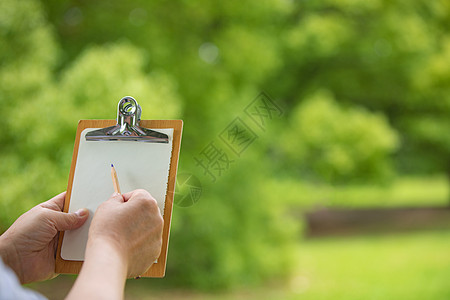 使用记事板在户外绘画记录手部特写图片
