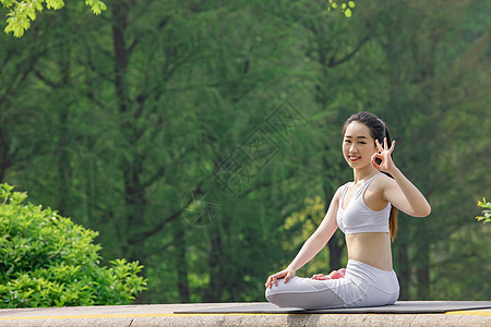 锻炼女女性在公园里做瑜伽比ok手势背景