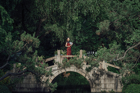 站在桥上手拿扇子的旗袍美女图片