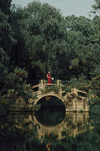 旗袍美女在桥上手拿扇子图片