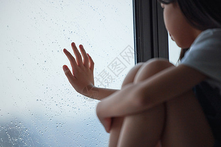 坐在窗边伤心孤单的小女孩背景图片