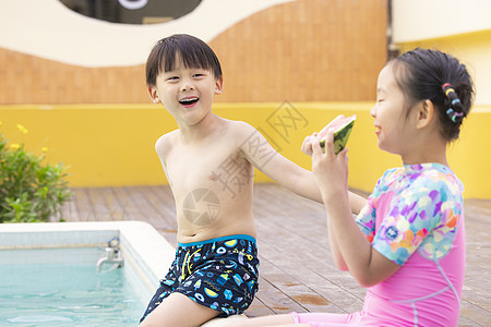 小朋友坐在泳池边吃西瓜玩耍图片