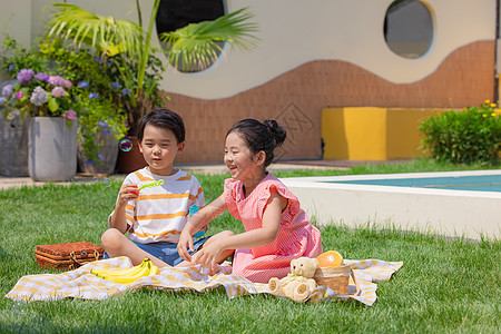 小男孩与小女孩草坪上野餐吹泡泡图片