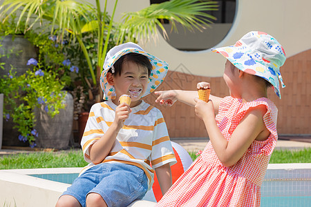 小男孩小女孩手拿冰淇淋坐在泳池边玩耍背景