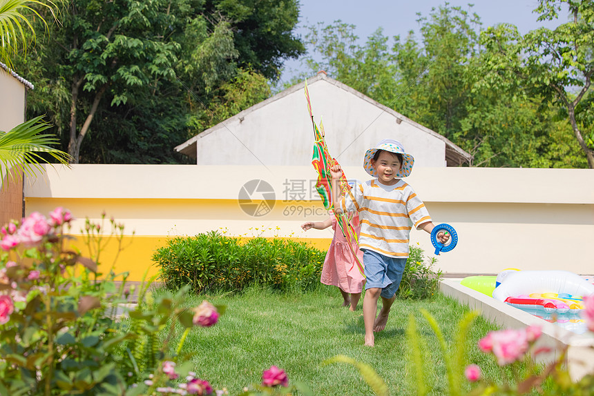 小男孩和小女孩在草坪奔跑玩风筝图片