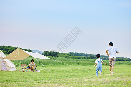 夏天模特小男孩和爸爸在草坪上追逐打闹背影背景
