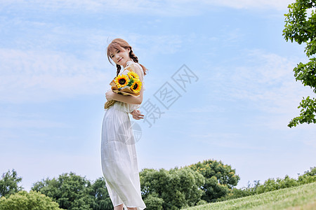 手拿鲜花的女生夏日美女手拿向日葵背景