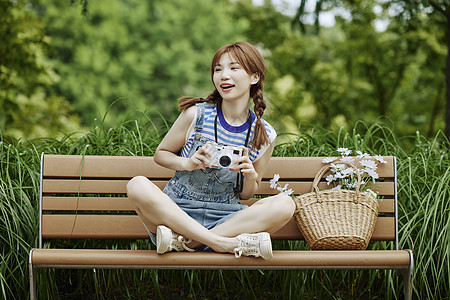坐在长椅上拍照的夏日美女图片