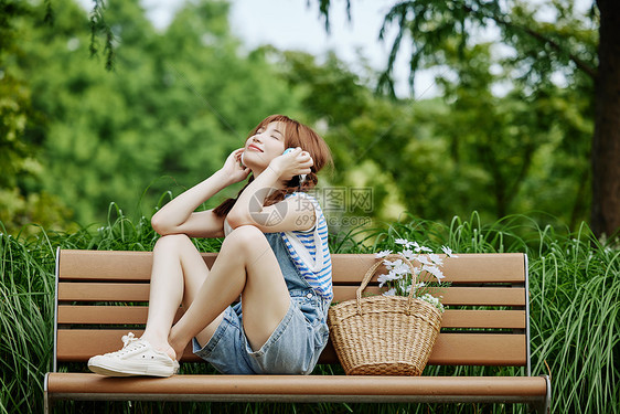 坐在长椅上听音乐的夏日美女图片