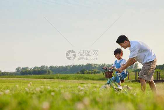 年轻爸爸陪伴小男孩学骑自行车图片