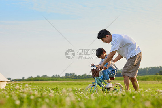 年轻爸爸陪伴小男孩学骑自行车图片