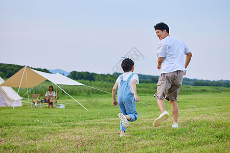 妈妈和小男孩小男孩和爸爸在草坪上追逐打闹背景