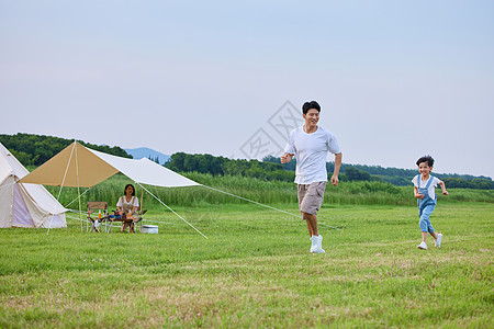 小男孩和爸爸在草坪上追逐打闹背景