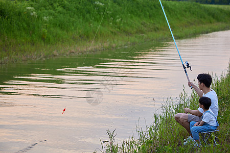 路亚钓鱼年轻爸爸带着儿子户外钓鱼背景