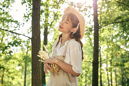 夕阳下手拿麦穗的夏日清新美女图片