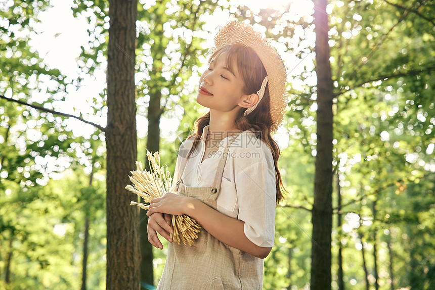 夕阳下手拿麦穗的夏日清新美女图片