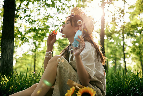 坐在草地前吹泡泡的清新夏日美女图片