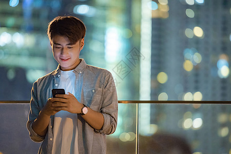 夜晚城市里看手机的男青年图片
