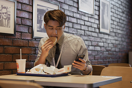 职场男性吃饭时看手机图片
