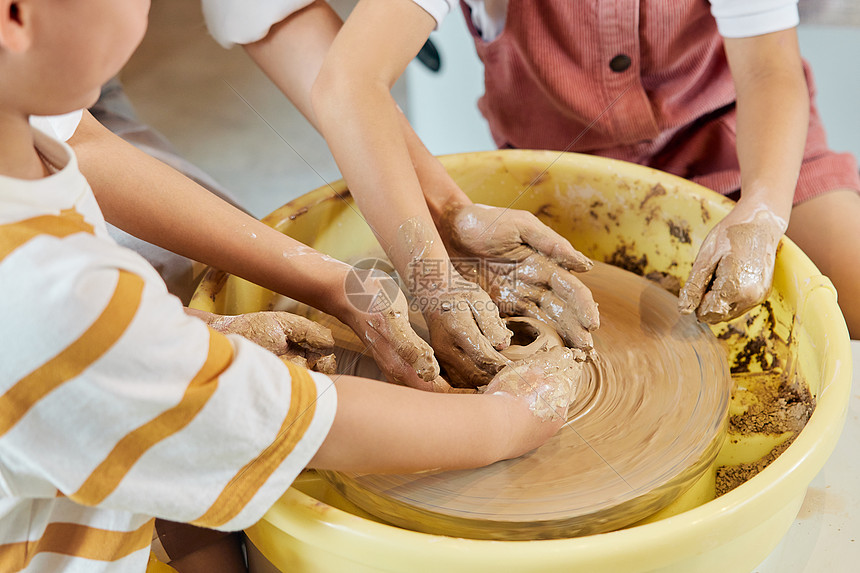 陶艺老师辅助小朋友制作陶艺品图片