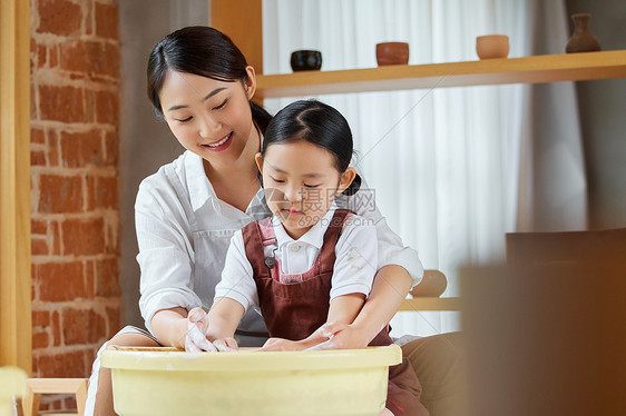 美女老师教小女孩制作陶艺作品图片