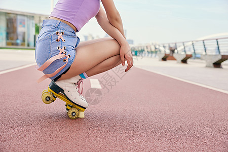 女性户外轮滑蹲在地上特写图片