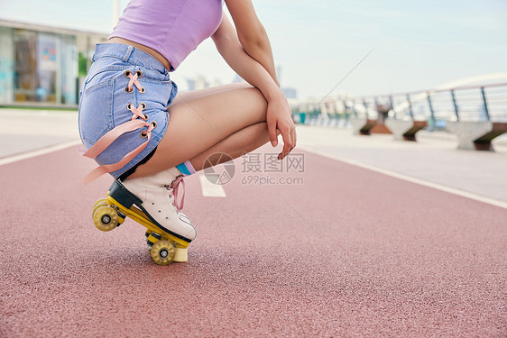 女性户外轮滑蹲在地上特写图片