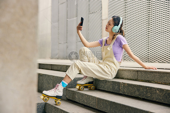 女性户外轮滑坐楼梯上听音乐图片