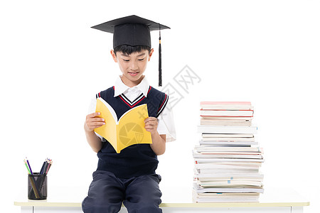 戴着学士帽看书的小男孩图片