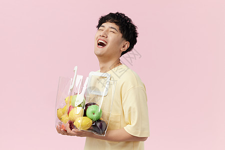 男生抱着水果袋开心大笑图片