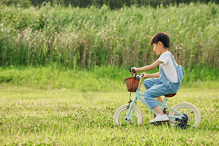 小男孩户外草地里骑自行车图片