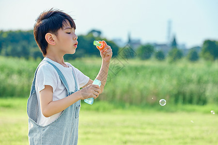 玩耍草坪小男孩户外游玩吹泡泡背景