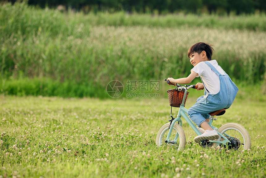 小男孩户外草地里骑自行车图片