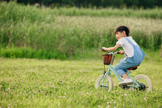 小男孩户外草地里骑自行车图片