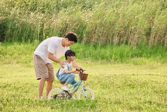 父子郊游爸爸教儿子骑自行车图片