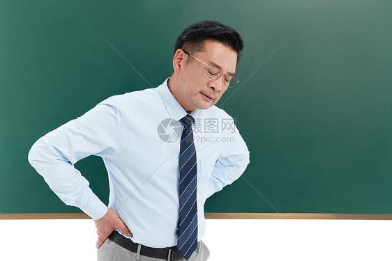 中年教授在黑板前双手撑腰面露疲惫图片