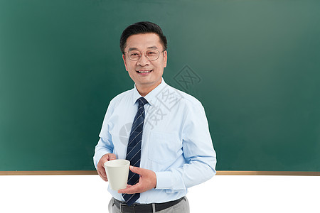 中年教授拿着水杯站在黑板前图片