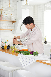 帅气的年轻男士在厨房做沙拉高清图片
