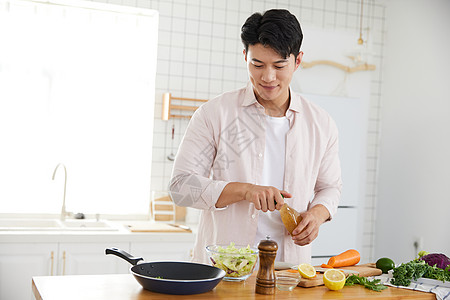 年轻男性做饭帅气的年轻男士在厨房做沙拉背景