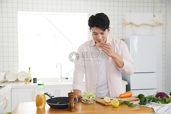帅气的年轻男士在厨房做沙拉图片