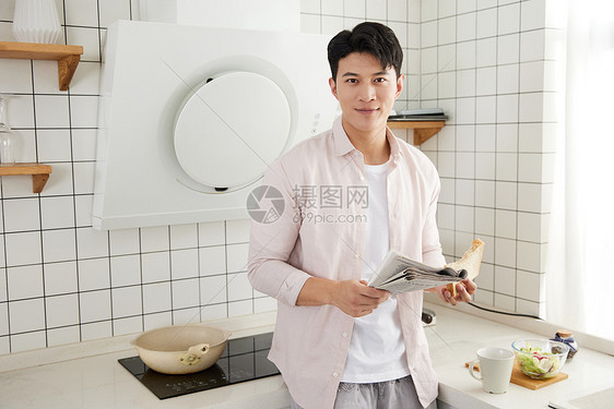 帅气的年轻男士在厨房读报纸图片