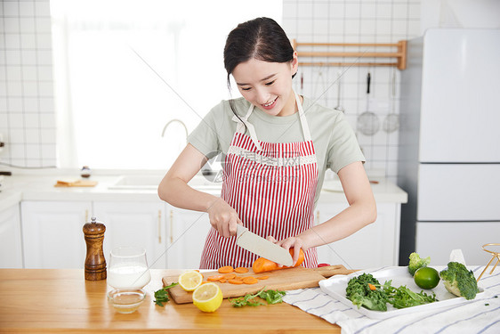 快乐的年轻女孩在厨房切菜图片