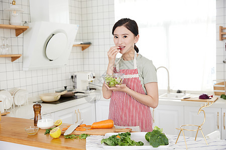 年轻女孩在厨房吃沙拉图片