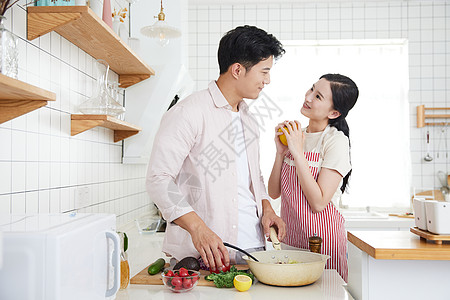 快乐的年轻情侣在厨房里做饭图片
